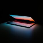 Eine moderne silberne und schwarze Heißluftfritteuse mit digitalem Touchscreen-Display steht auf einer Küchenarbeitsplatte, umgeben von frischen Zutaten und Pommes in einer Schale, die das fettfreie Kocherlebnis symbolisieren.